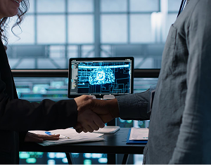Two business people shaking hands in a tech-focused office, signifying expert guidance.