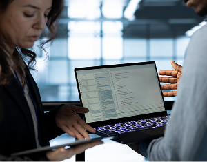 Two professionals discussing technical code on a laptop, offering expert guidance.
