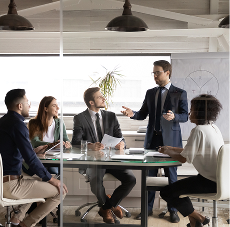 A manager in a suit leads a corporate training session for a diverse team in a modern conference room.