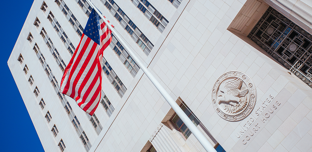 United States Court House with American flag and detailed eagle seal on stone facade.