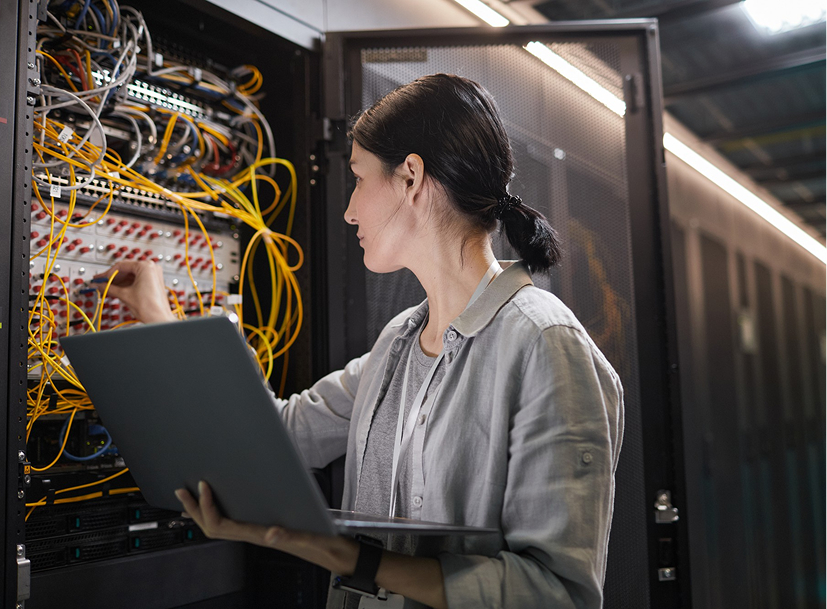 Woman managing server cables in a server rack, representing an IT career track.