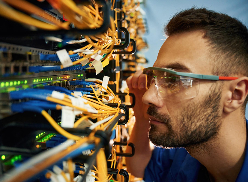 IT professional in safety glasses inspecting server rack cables, a rewarding career track in technology.