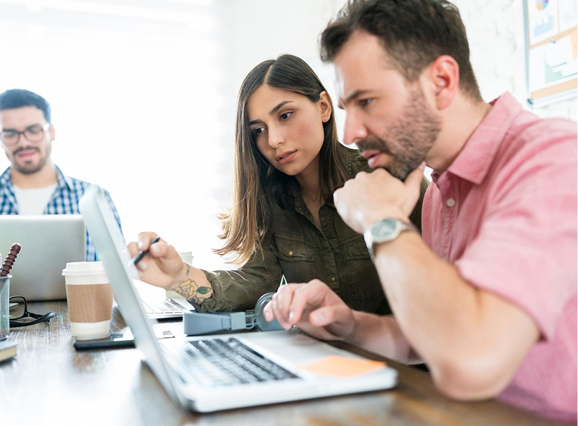 Two colleagues discuss their career track on a laptop.