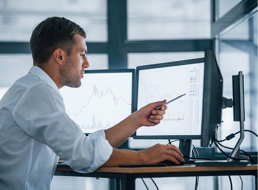 Man analyzing complex data on multiple monitors, relevant to a Cyber Security Track.